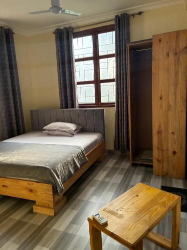 a bedroom with a bed and a table and a window at Hakuna matata Apartments in Zanzibar City