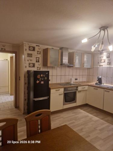a kitchen with white cabinets and a black refrigerator at Justyna-Sebastian FE-WO in Paderborn