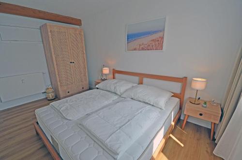 a bedroom with a large bed and a table with a lamp at Am Ufer Top 13 in Dranske