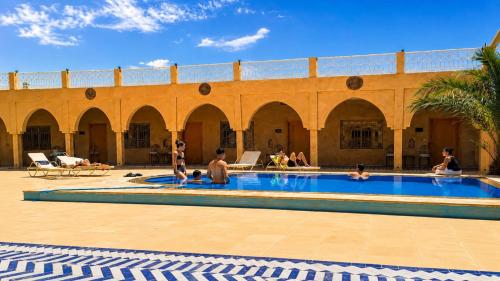 a group of people sitting in a swimming pool at Riad Akabar Merzouga in Merzouga