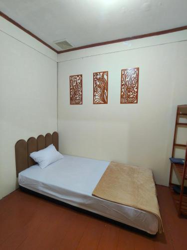 a bed in a room with three pictures on the wall at Ghaniya Homestay in Bonto