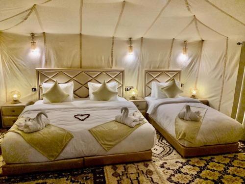a bedroom with two beds in a tent at Royal Erg Chebbi Luxury Camp in Adrouine