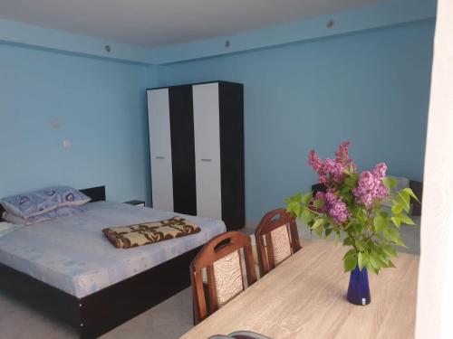 a bedroom with a bed and a table with a vase of flowers at Casa Dina in Băile Herculane
