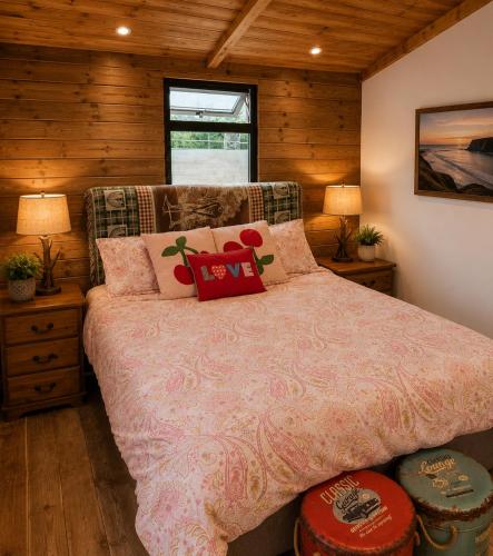 a bedroom with a bed with a pink comforter at Oceanview Cosy Cabin in Drumaville