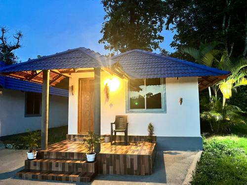 a small white house with a blue roof at Misty field view Homestay in Ponnampet