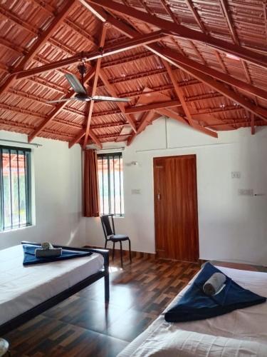 a room with two beds and a chair in it at Misty field view Homestay in Ponnampet