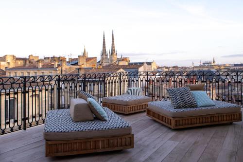 three benches on a balcony with a view of a city at Hôtel Singulier Bordeaux - Boutique Hôtel & Spa Anne Semonin in Bordeaux