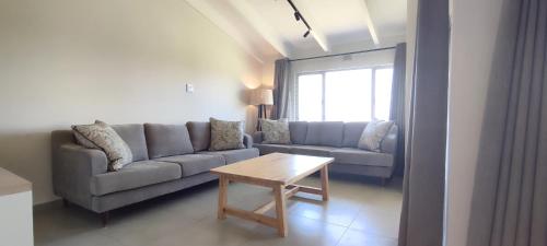 a living room with a couch and a table at 4 Chaka's Rocks Chalets - The Beach Cottage in Ballito