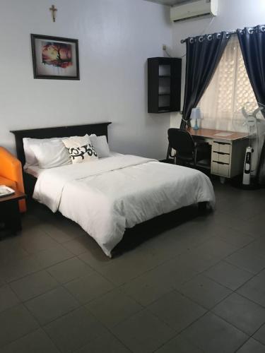 a bedroom with a bed and a desk with a computer at Engelbert Beyer Centre in Ibadan