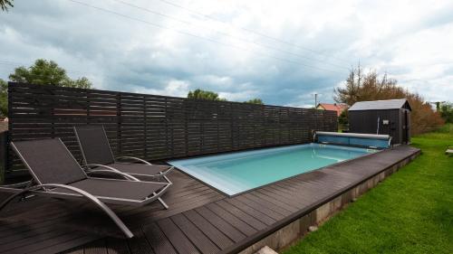 a swimming pool on a wooden deck with two chairs at Flatbook Stegna Południowa Apartamenty z Basenem in Stegna