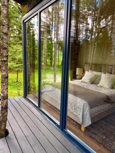 a glass room with a bed in a forest at For-rest Užsienis in Kazitiškis