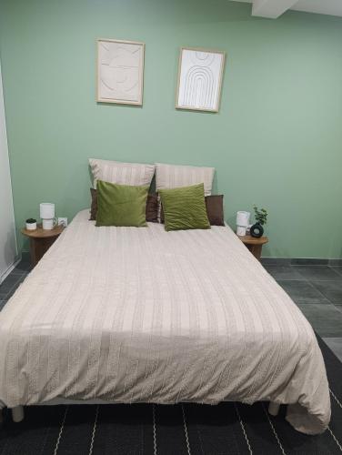 a bedroom with a large bed with green pillows at Studio Boulazac proche Palio in Boulazac