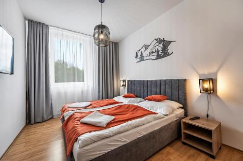 a bedroom with a large bed with an orange blanket at Hotel Spolcentrum in Jezersko