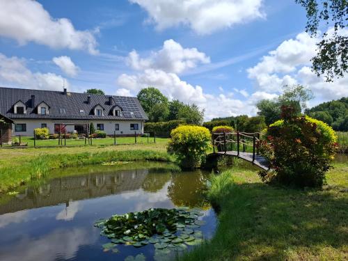 a bridge over a pond in front of a house at Apartamenty TUTERRA I in Zabagnie