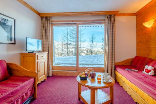 Zimmer mit Sofa, Tisch und Fenster in der Unterkunft Lagrange Vacances Aspen in La Plagne