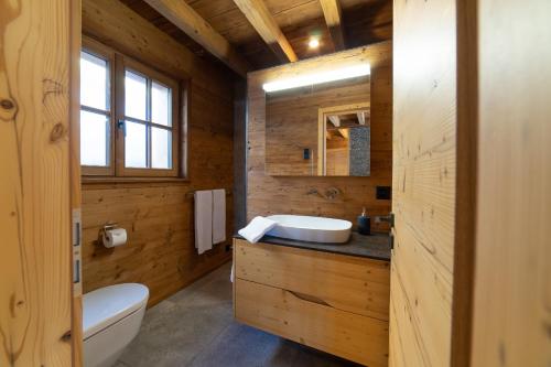 a wooden bathroom with a sink and a toilet at Chalet Frümsel - Luxury & Bergblick in Wildhaus