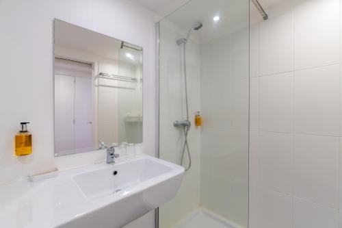 a white bathroom with a sink and a shower at Florasol Residence Hotel - Dorisol hotels in Funchal