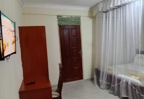 a bedroom with a wooden door and a desk and a window at Luanda Road View Hotel in Luanda