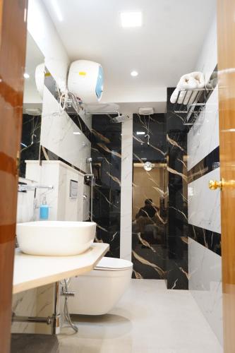 a bathroom with a white toilet and a black tile wall at Hotel Maruti in Mandsaur
