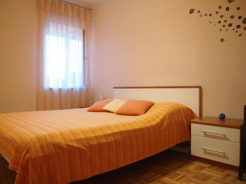 ein Schlafzimmer mit einem Bett mit orangefarbener Bettwäsche und einem Fenster in der Unterkunft Holiday Home Oliva in Bilice