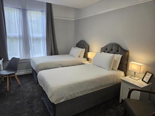 a hotel room with two beds and a chair at Best Western Stoke on Trent City Centre Hotel in Stoke on Trent