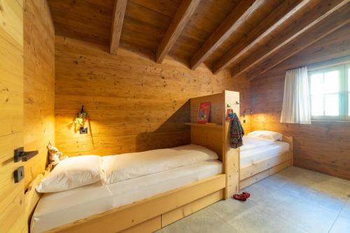 a bedroom with two beds in a wooden room at Chalet Frümsel - Luxury & Bergblick in Wildhaus