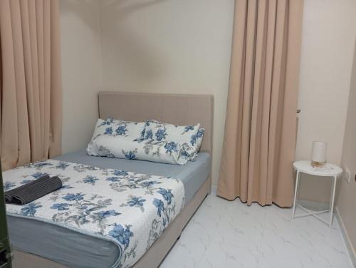 a bedroom with a bed with blue and white sheets and a table at Adeeb Homestay in Tumpat
