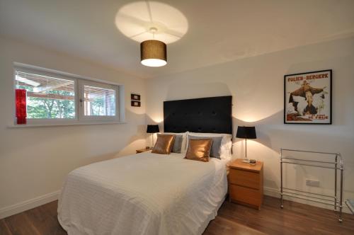 een slaapkamer met een groot wit bed en een lamp bij The Garden Apartment, Near Airport & City in Manchester