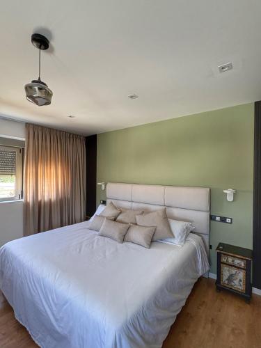 a bedroom with a white bed with a green wall at Santiurde Suites in Quintanilla de Arriba