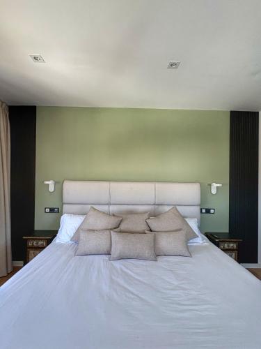 a large white bed with three pillows on it at Santiurde Suites in Quintanilla de Arriba