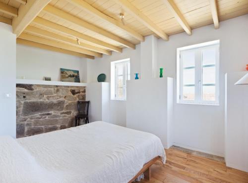 a bedroom with a white bed and a stone wall at Casa Caseiros, Couso in Gondomar