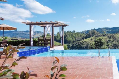 a swimming pool with a gazebo and a view of mountains at Pousada Estância das Montanhas Boutique in Águas de Lindoia