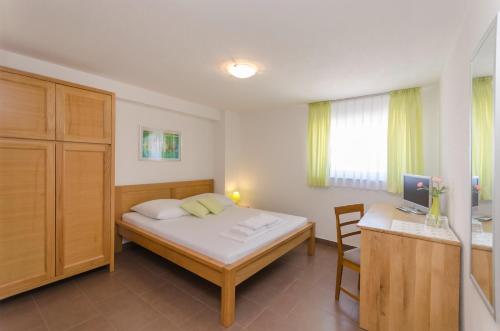 a bedroom with a bed and a desk with a computer at Zimmer Katarina in Vodice