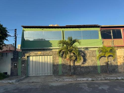 a green building with palm trees in front of it at Casa Espaçosa - Caminhe até a Orla de Atalaia 650m in Aracaju