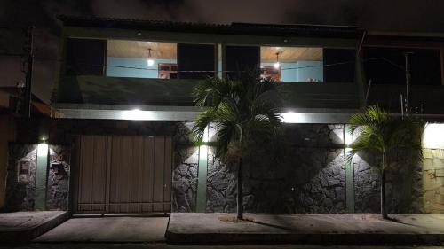 a building with palm trees in front of it at night at Casa Espaçosa - Caminhe até a Orla de Atalaia 650m in Aracaju