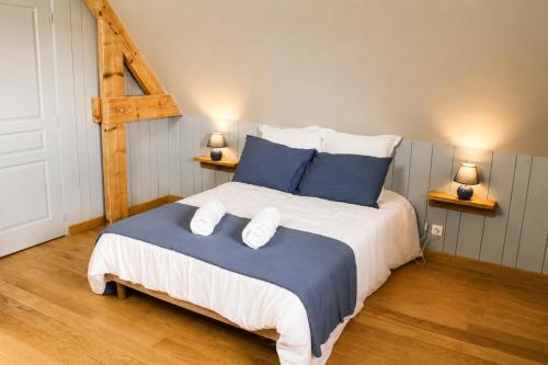 a bedroom with a large bed with blue pillows at Cottage de charme avec piscine et vue panoramique - 6-8 pers Pays d'Auge in Vimoutiers