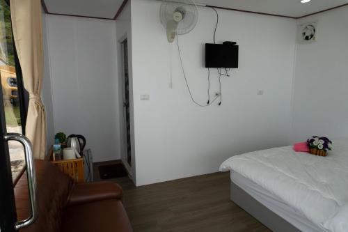 a bedroom with a bed and a fan on the wall at ฟลายมี ภูทับเบิก in Ban Maeo Thap Boek