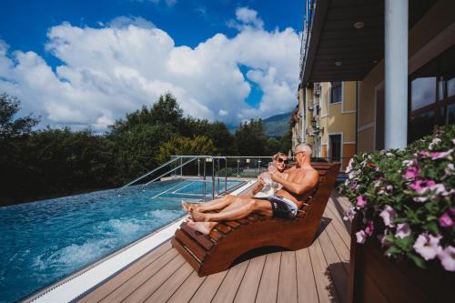 a man and a woman sitting on a bench next to a pool at Grand Hotel Praha in Tatranská Lomnica
