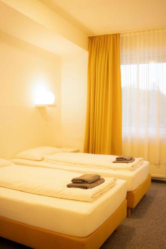 two beds in a hotel room with a window at Kotlina smart hotel in Rožňava
