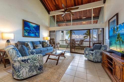 a living room with a blue couch and chairs and a tv at Hale Mahina #B-405 in Honokowai