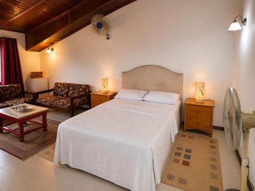 a bedroom with a white bed and a living room at Roc Heights in Bakau