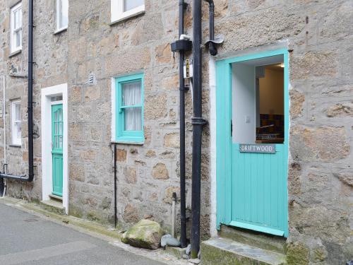 a stone building with a blue door and windows at Driftwood in St Ives