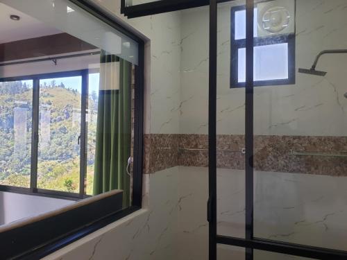 a bathroom with a glass door and a window at Ella Mount Relax Cottage in Ella