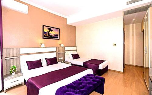 a hotel room with two beds and a purple couch at Nil Hotel İstanbul City Center in Istanbul