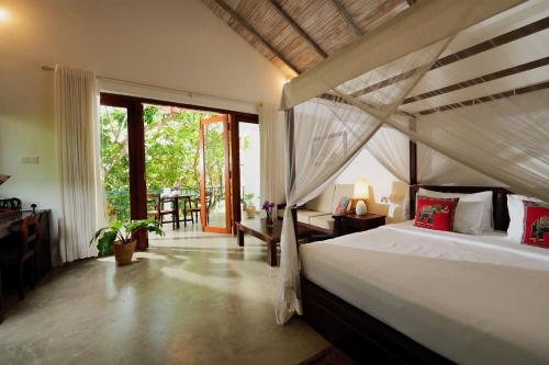 a bedroom with a bed and a large window at Ceylon Olive Galle in Galle