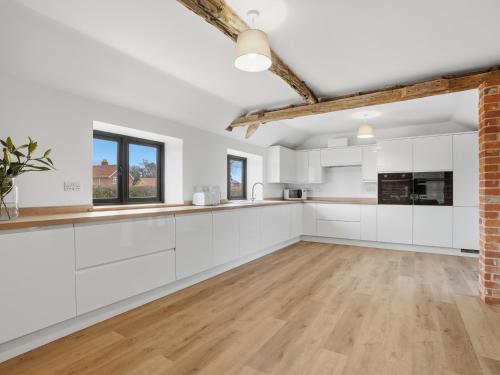 an open kitchen with white cabinets and wood floors at Partridge Barn - Uk52217 in Corton