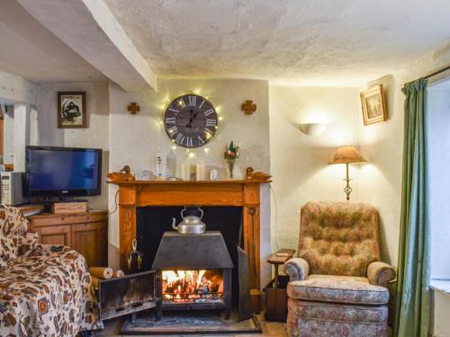 a living room with a fireplace and a clock on the wall at Hoopers Farmhouse - Uk36307 in Tilshead