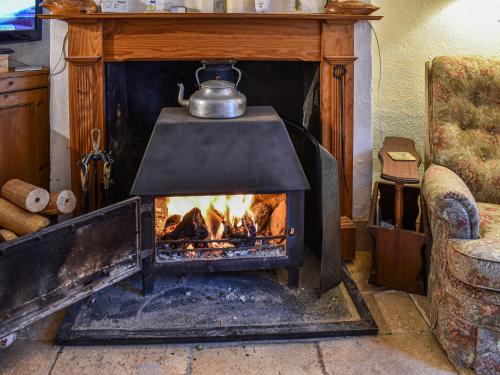 a fireplace with a tea kettle on top of it at Hoopers Farmhouse - Uk36307 in Tilshead