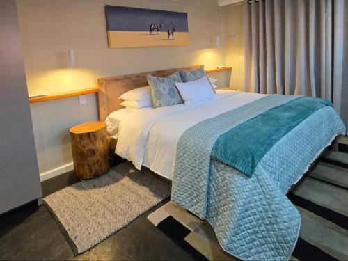 a bedroom with a large bed with a blue blanket at Eternal @ Yzerfontein in Yzerfontein