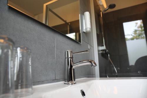 a bathroom sink with a faucet and a mirror at Hôtel Restaurant Lamy in Troisvierges